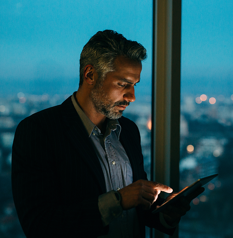 Man standing next to a window holding a tablet with modern graphics